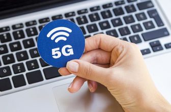 Henkilö pitää kädessään 5G-symbolia työpisteellä
