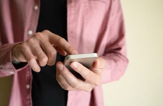 Mies tarkastelee älypuhelinta käsissään