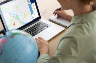 Henkilö työskentelee kannettavan tietokoneen ääressä ja tekee muistiinpanoja